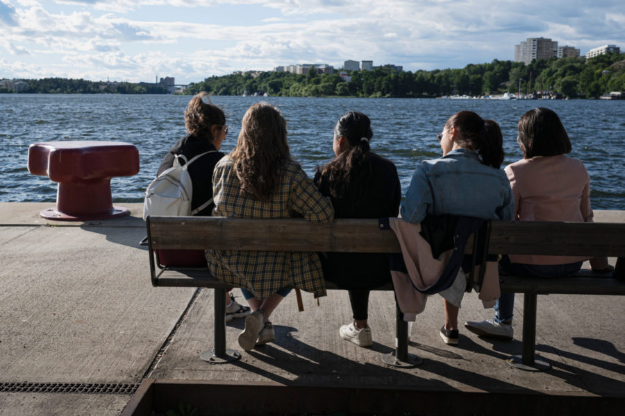 En grupp unga tjejer sitter på en bänk vid Hornsbergs strand, Stockholm 2020.