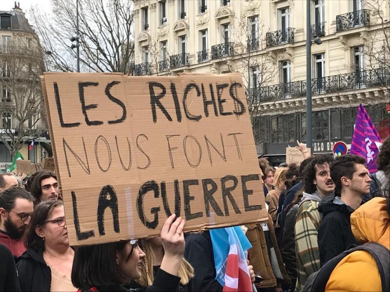 De rika krigar mot oss står det på plakatet som bärs upp av en kvinna under en demonstration mot pensionsreformen i Frankrike.