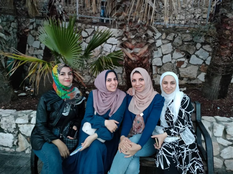 Fyra palestinska kvinnor från organisationen Aisha sitter på en låg mur i Gaza.