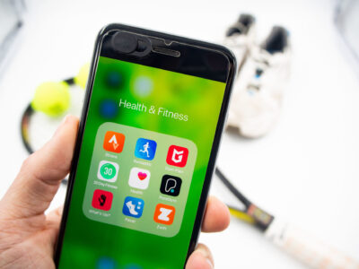 En hand håller i en mobil och på skärmen visas olika hälsoappar.