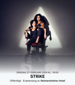 Två kvinnor, bandmedlemmar i bandet Strike sitter på en stol.