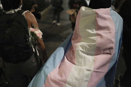 Ung person i rullstol med en blombukett fastsatt på stolen och bredvid en transflagga