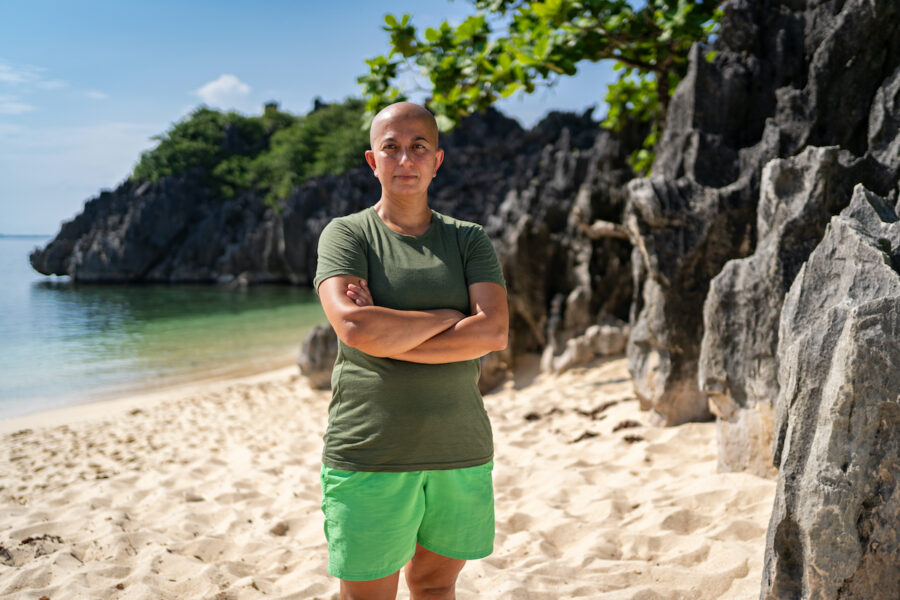Zayera Khan, en av årets Robinsondeltagare, i shorts och t-shirt på en strand I solen.