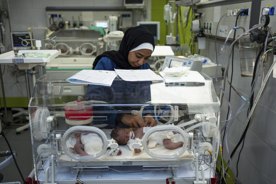 En sjukvårdsanställd sköter om ett litet spädbarn i kuvös