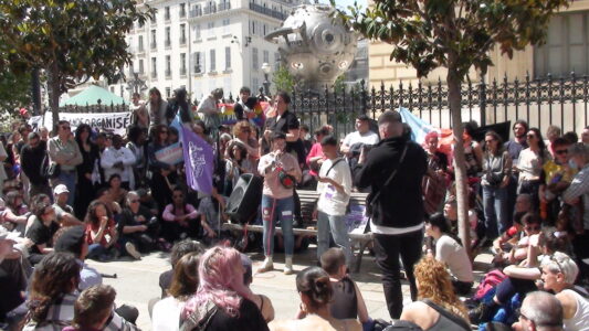 en person står och pratar i mikrofon och runt om sitter och stor många personer och lyssnar