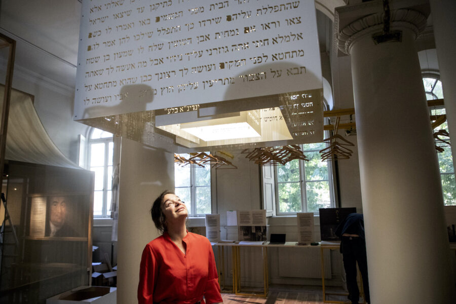 kvinna tittar upp mot ett ljusinsläpp i taket i en muséemiljö