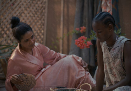 Två kvinnor, en arabiska och en afrikansk kvinna sitter bredvid varandra på golvet