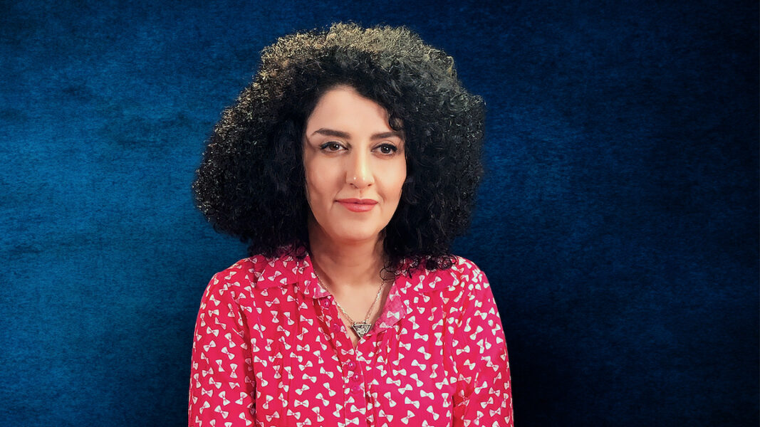 Kvinna Narge Mohammadi med mörkt lockigt hår och röd blus