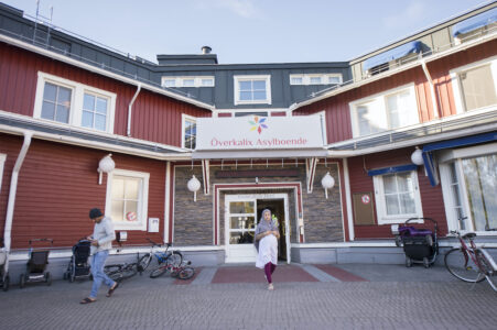 Röd byggnad och två personer på gårdsplanen framför.