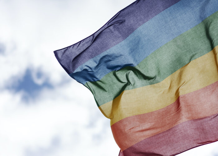 prideflagga fladdrar i vinden med blå himmel bakom