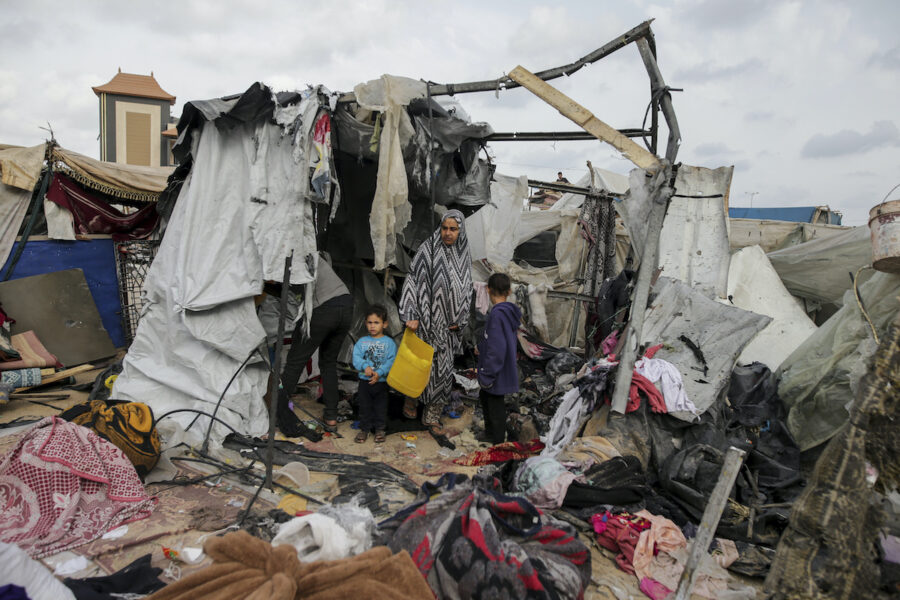 En kvinna och två barn bland brända tältrester i krigets Gaza