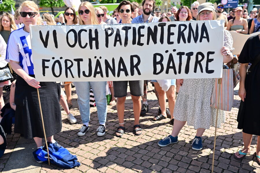 En grupp demonstranter håller i en banderoll där det står Vi och patienterna förtjänar bättre