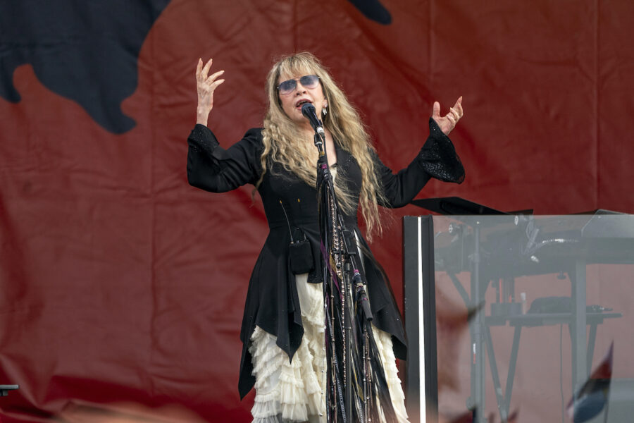 Sångerskan Stevie Nicks på scen framför en mikrofon och med armarna i luften