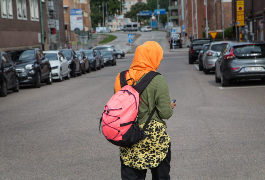 Kvinna i orange slöja och ryggsäck.