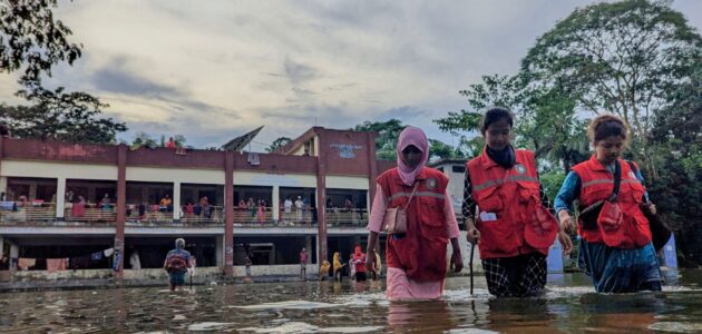 Kvinnor går i djupt vatten efter översvämning.