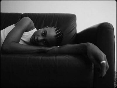 En kvinna ligger ner på en soffa och tittar in i kameran.