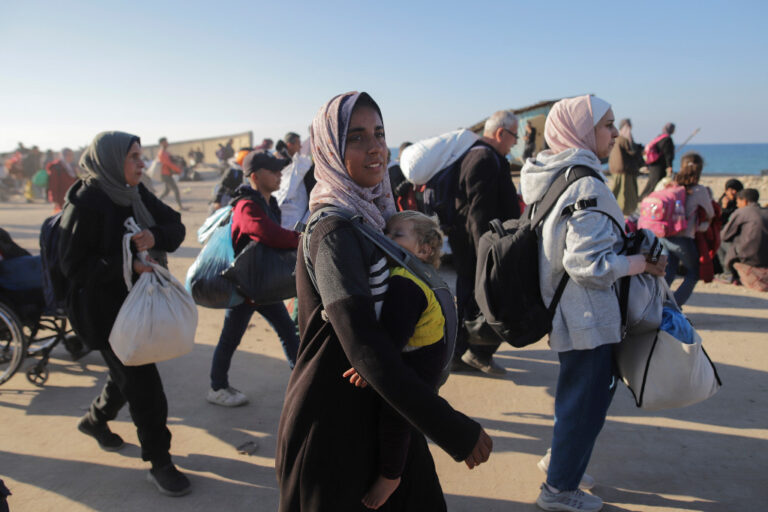 Palestinsk kvinna bär sitt barn på bröstet.