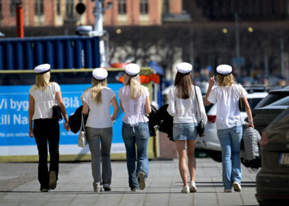 Fem tjejer i studentmössa promenerar.