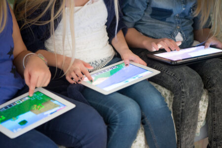 Tre flickor sitter med plattor och spelar.