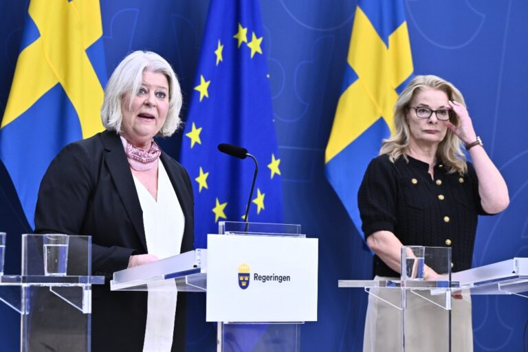 Camilla Waltersson Grönwall (M) och Lotta Edholm (M) framför två Sverigeflaggor och en EU-flagga.