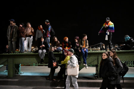 Personer med en Prideflagga protesterar.