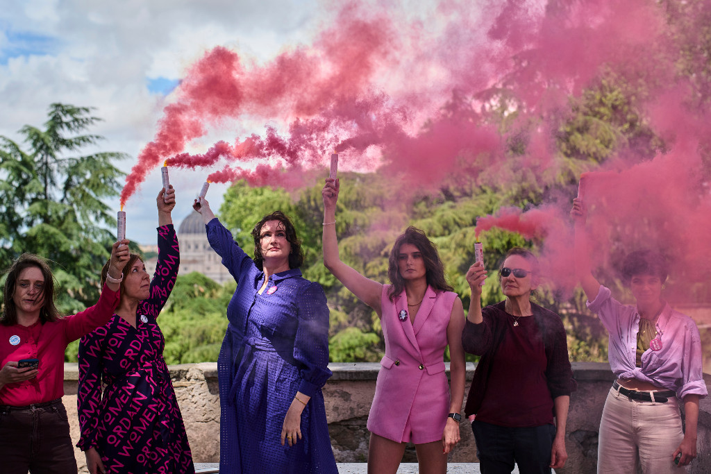Kvinnor släpper ut rosa rök med Sixtinska kapellet i bakgrunden.