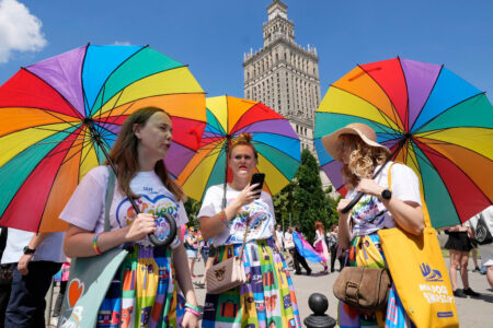 Tre kvinnor med parasoll i regnbågsfärger.