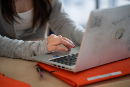 Flickas hand på tangentbord på laptop.