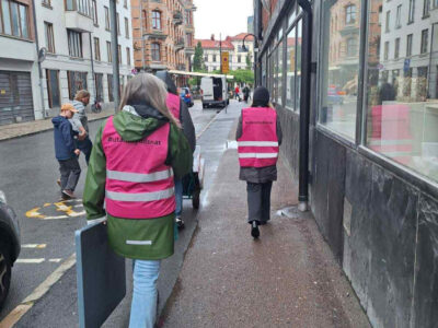 Kvinnor med rosa västar går längs en trottoar.