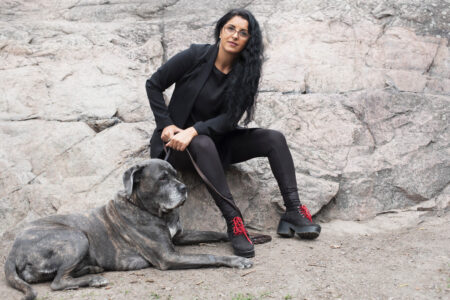 Ida Ali Lindqvist med sin hund mot en stenmur.