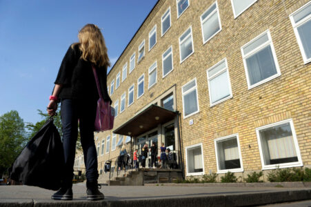 Flicka på skolgård och flera elever en bit bort.