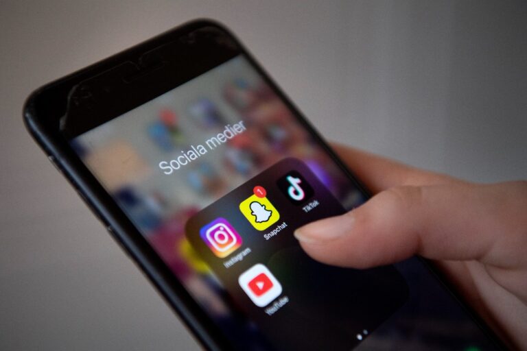 Hand håller i mobil där apparna Instagram, Snapchat, Tiktok och Youtube syns.