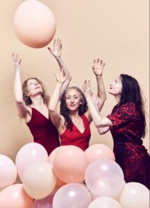 Tre kvinnor med rosa ballonger.