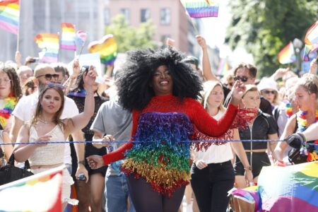 Kvinna i glittrig regnbågsklänning i Stockholm Pride 2025.