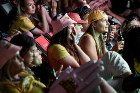 Publik tittar på fotboll på storbildsskärm.