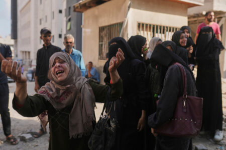 Palestinsk kvinna höjer händerna i sorg.