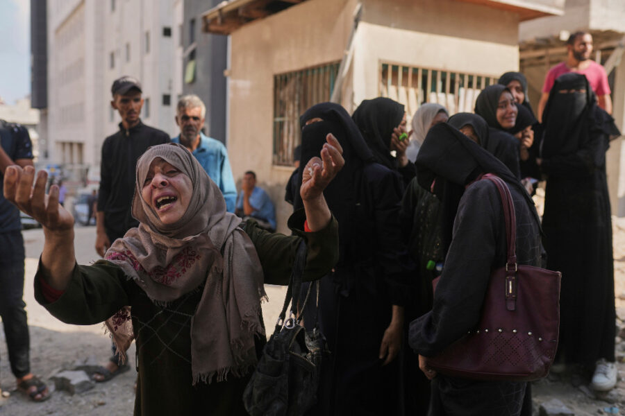 Palestinsk kvinna höjer händerna i sorg.
