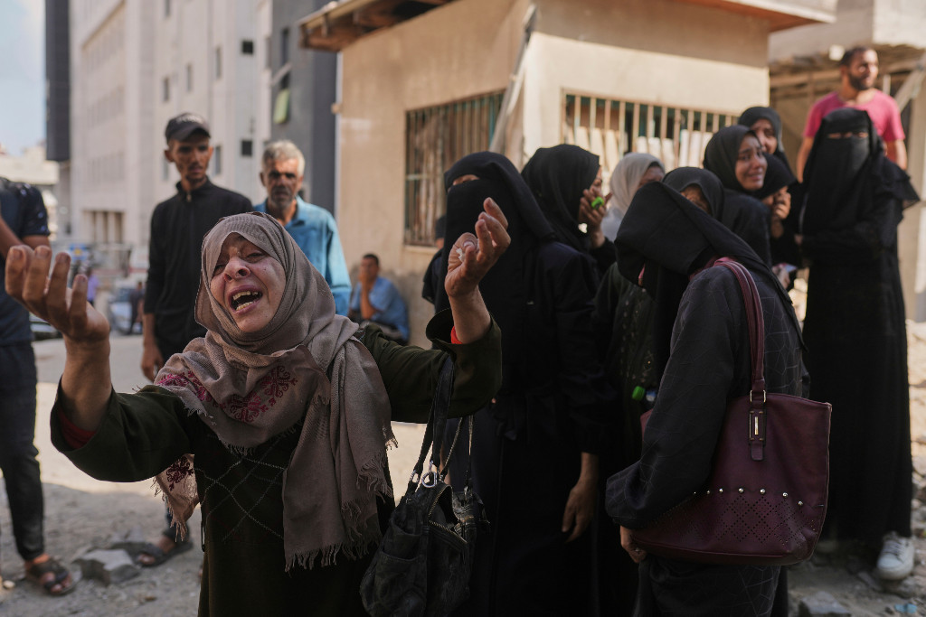 Palestinsk kvinna höjer händerna i sorg.