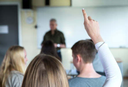 En gymnasieelev med långt hår håller upp sin hand.
