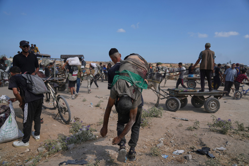 En palestinsk man bär på kroppen av en man som dödades när han försökte få tag på mat.