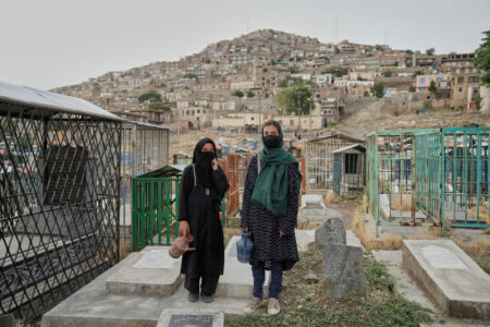 Två flickor står med vattenkannor i händerna.