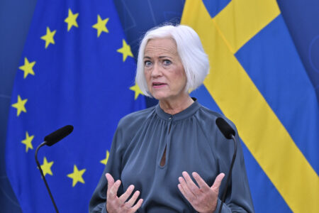 Acko Ankarberg Johansson framför EU- och Sverigeflaggor.