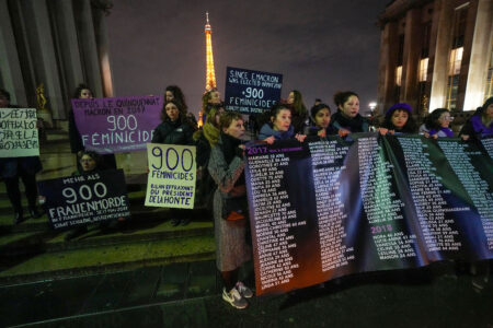 Kvinnor med plakat i skymningen med Eiffeltornet i bakgrunden.