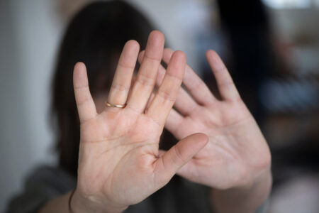 Kvinna håller upp sina händer i värjande gest.