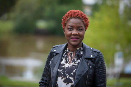 Cartrine Anyango med rött hår och svart jacka.