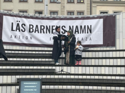 Två kvinnor och ett barn står på en trappa med mikrofon.