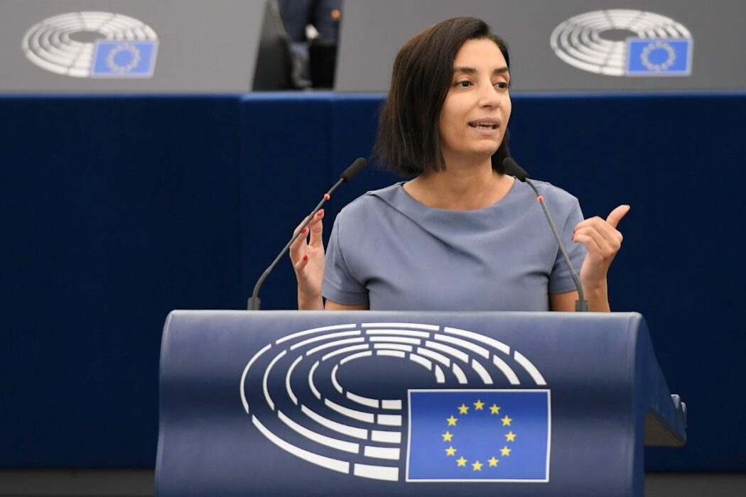 Evin Incir (S) i talarstol med EU-flagga på.