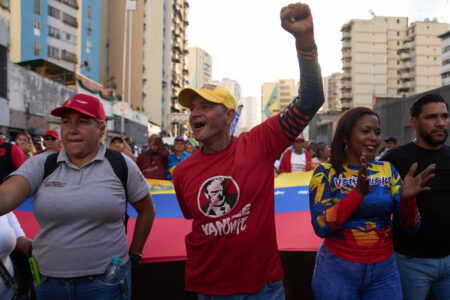 Demonstranter med banderoll och en knuten hand i luften.