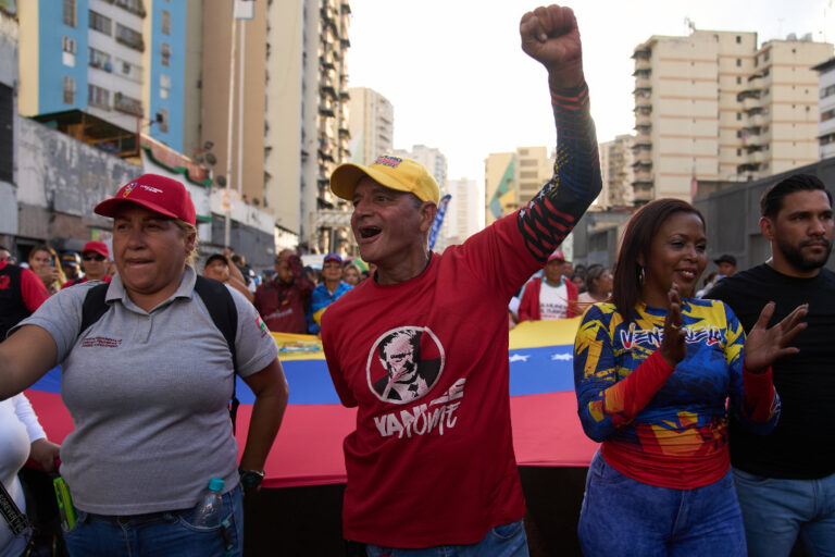 Demonstranter med banderoll och en knuten hand i luften.