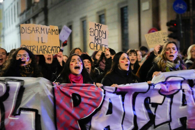 Kvinnor demonstrerar med banderoll och plakat.